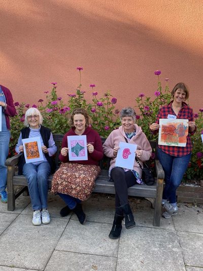Ladies holding up their prints in the walled garden.