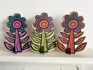 colourful linocut printed flowers on wood standing in a row