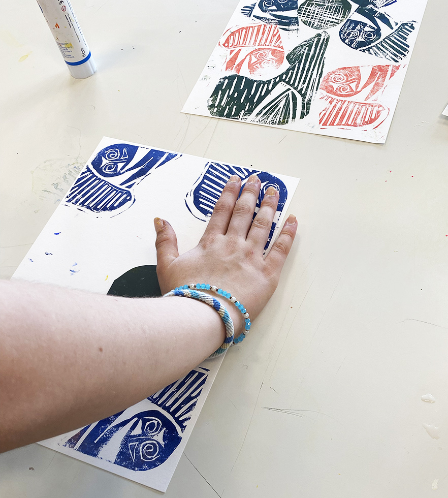 child's hand printing a linocut print