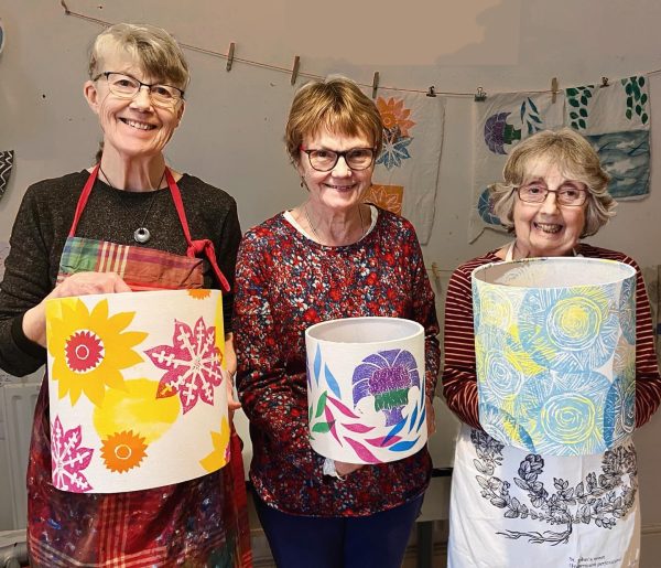 three smiling ladies holding their hand printed lampshades