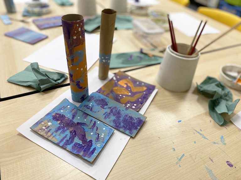 Table showing painted cardboard tubes and a palette with paint in.