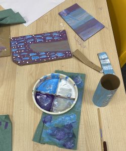 Table showing painted cardboard tubes and a palette with paint in.