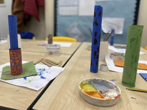 Table showing painted cardboard tubes and a palette with paint in.
